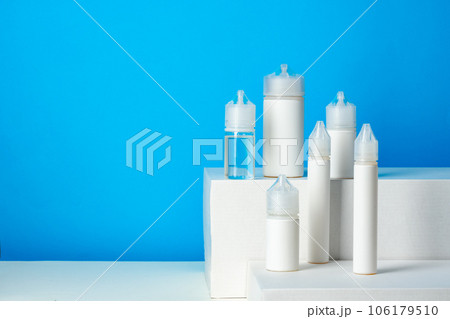 Black electronic cigarettes liquid bottles on blue background Black electronic cigarettes liquid bottles on blue background 106179510