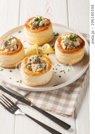 French puff pastry Vol au vent filling with chicken, cream and mushroom closeup on the plate on the wooden table. Vertical French puff pastry Vol au vent filling with chicken, cream and mushroom closeup on the plate on the wooden table. Vertical 106180398