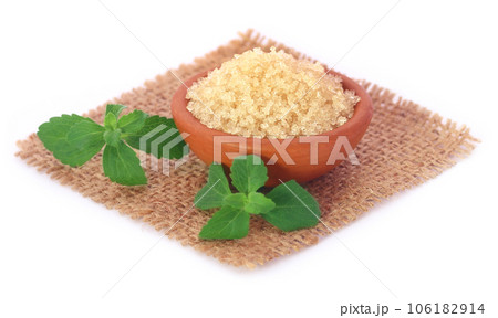 Coarse crystals of brown sugar with stevia leaves Coarse crystals of brown sugar with stevia leaves 106182914