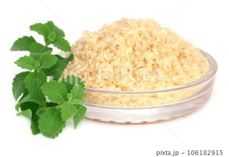 Coarse crystals of brown sugar with stevia leaves Coarse crystals of brown sugar with stevia leaves 106182915