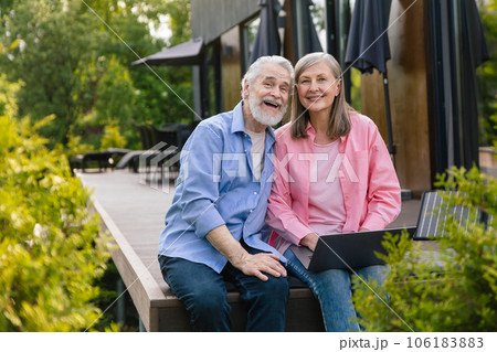 Man and woman sitting on house porch with solar panel using notebook. 106183883