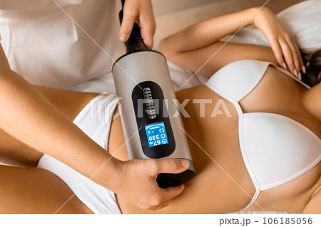 Spa worker massages woman client belly with cellulite remover. Appliance for smoothing skin relief and eliminating flabbiness in adulthood Spa worker massages woman client belly with cellulite remover. Appliance for smoothing skin relief and eliminating flabbiness in adulthood 106185056
