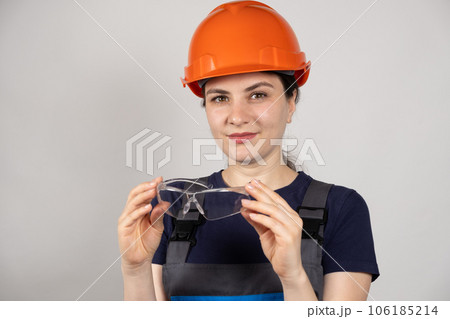 A woman in a protective helmet, glasses and overalls on a white background with space for text. A woman in a protective helmet, glasses and overalls on a white background with space for text. 106185214