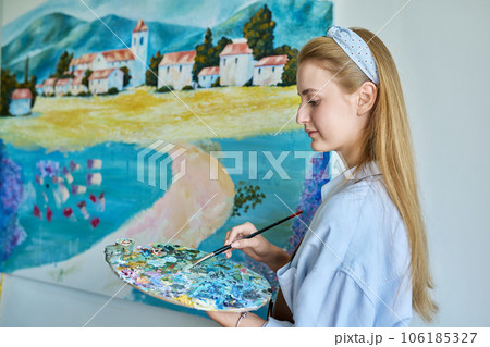 Young woman artist painting picture on canvas on wall Young woman artist painting picture on canvas on wall 106185327