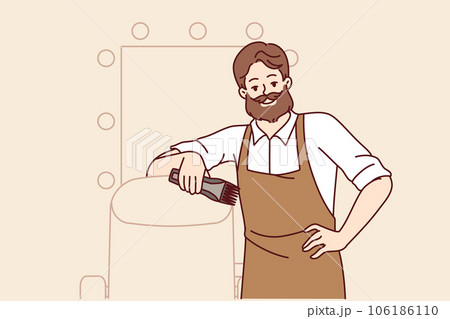 Bearded man hairdresser works in barbershop and smiles, standing near chair for client and mirror Bearded man hairdresser works in barbershop and smiles, standing near chair for client and mirror 106186110