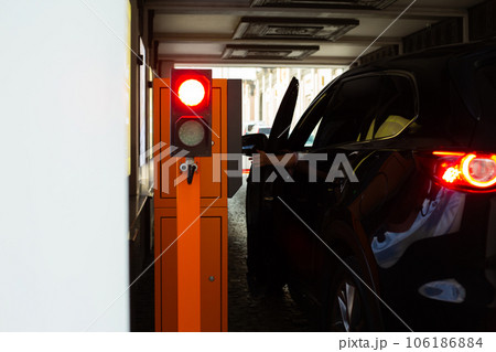 Woman's hand reaches out from the open car door at the parking lot entrance. Difficulty pressing the parking button at the barrier Woman's hand reaches out from the open car door at the parking lot entrance. Difficulty pressing the parking button at the barrier 106186884