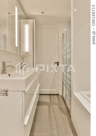 a bathroom with white walls and wood flooring on the wall, along with a bathtub next to it a bathroom with white walls and wood flooring on the wall, along with a bathtub next to it 106188713