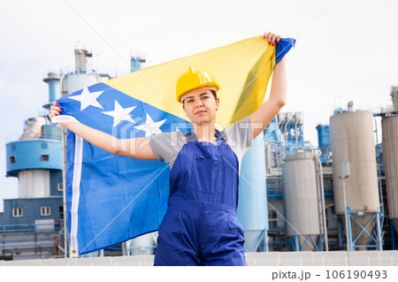 Worried girl in work clothes and hardhat with flag of bosnia standing in front of industrial scenery Worried girl in work clothes and hardhat with flag of bosnia standing in front of industrial scenery 106190493