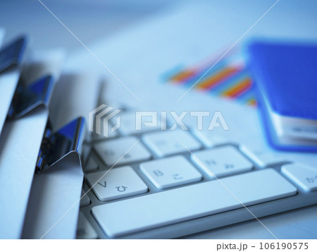 テーブルに置かれたグラフ、キーボード、書類、手帳 106190575
