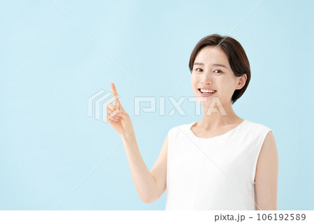 女性　指差し　ブルーバック  106192589