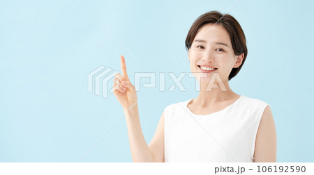 女性　指差し　ブルーバック  106192590