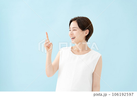 女性　指差し　ブルーバック  106192597