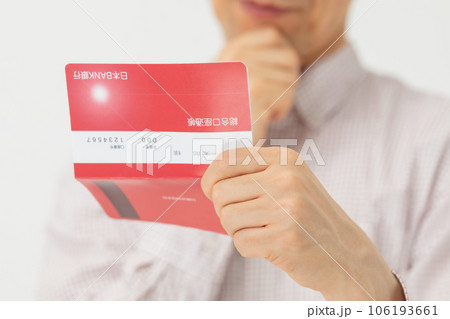 通帳を見て悩む男性 通帳を見て悩む男性 106193661