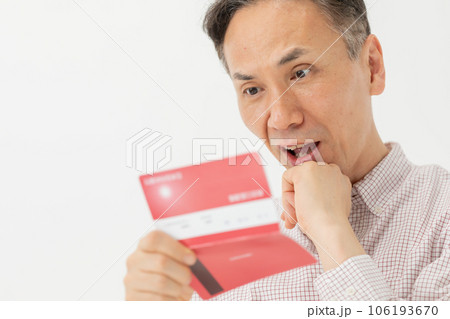 通帳を見て悩む男性 106193670
