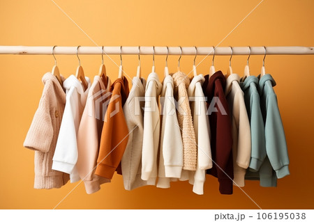 stylish baby clothes hanging on rack against color background stylish baby clothes hanging on rack against color background 106195038