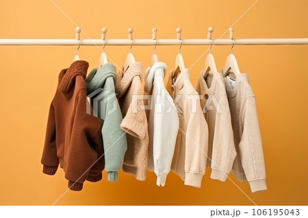 stylish baby clothes hanging on rack against color background 106195043
