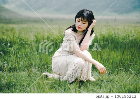 草原にしゃがんでいる白いワンピースを着た女性 草原にしゃがんでいる白いワンピースを着た女性 106195212