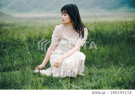 草原にしゃがんでいる白いワンピースを着た女性 草原にしゃがんでいる白いワンピースを着た女性 106195218