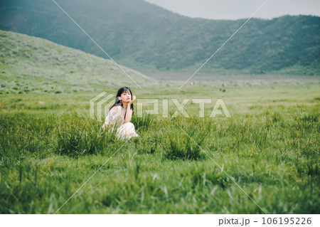 草原にしゃがんでいる白いワンピースを着た女性 106195226
