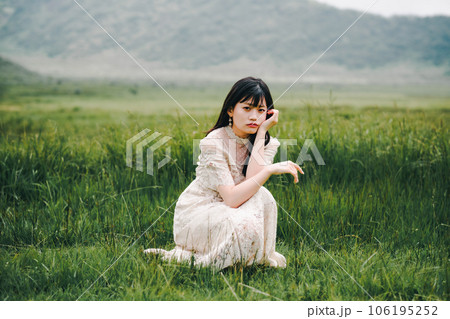 草原にしゃがんでいる白いワンピースを着た女性 草原にしゃがんでいる白いワンピースを着た女性 106195252