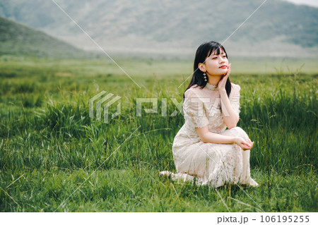 草原にしゃがんでいる白いワンピースを着た女性 草原にしゃがんでいる白いワンピースを着た女性 106195255