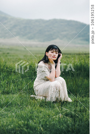 草原にしゃがんでいる白いワンピースを着た女性 草原にしゃがんでいる白いワンピースを着た女性 106195258