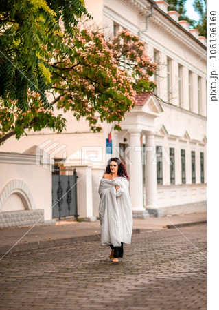 Woman city blanket. Morning in the big city. A blonde woman in a white blanket is enjoying in the city center. Photographed for social media Woman city blanket. Morning in the big city. A blonde woman in a white blanket is enjoying in the city center. Photographed for social media 106196160