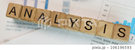 Word analysis collected from wooden cubes with magnifying glass and pen on financial report. 106196593