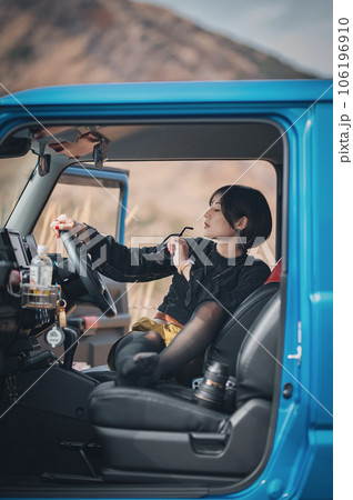 車のドアを開け休憩中の女性がサングラスを左手に持っている 車のドアを開け休憩中の女性がサングラスを左手に持っている 106196910