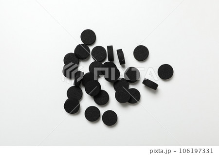 Tablets of activated carbon on a light background 106197331