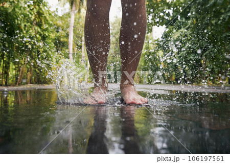 Man jumping with bare feet into puddle 106197561