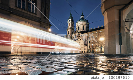 Light trail of tram passing between historical buildings at night 106197619
