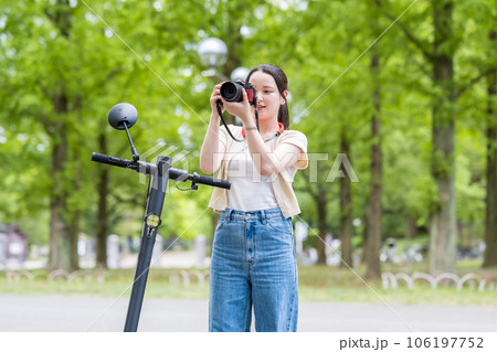 電動キックボードで移動しながら趣味のカメラ撮影をする若くて可愛い女性｜カメラ女子イメージ 106197752
