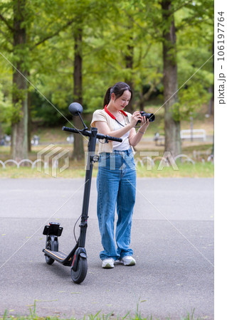電動キックボードで移動しながら趣味のカメラ撮影をする若くて可愛い女性｜カメラ女子イメージ 106197764