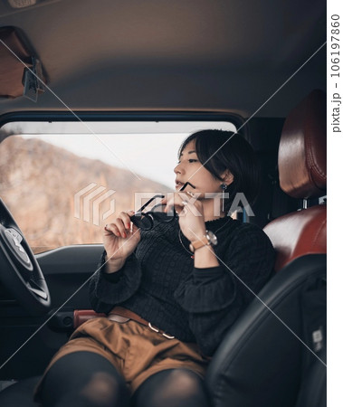 運転席で横向きにサングラスを手に休む女性 運転席で横向きにサングラスを手に休む女性 106197860