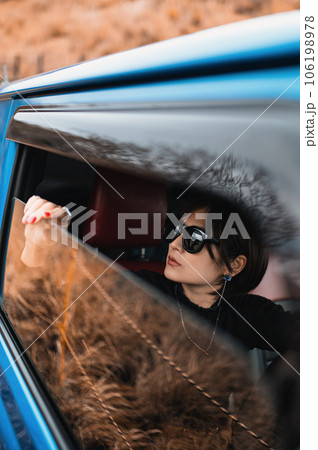 少し開けた車の窓から外を見るサングラスの女性 少し開けた車の窓から外を見るサングラスの女性 106198978