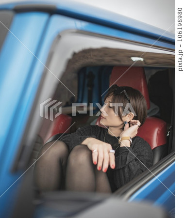 車の助手席で膝を立てピアスを触る女性 106198980