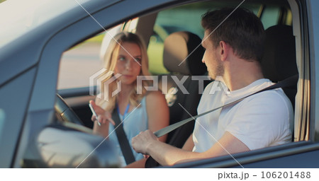 Young man and driving school instructor with clipboard talking in car. Man listening to instructor in car learning to drive. Young man and driving school instructor with clipboard talking in car. Man listening to instructor in car learning to drive. 106201488