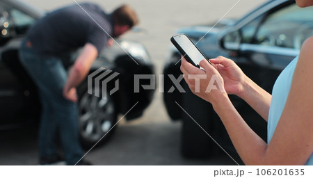 Woman insurance agent inspects damage to a man car and makes notes on a smartphone. Woman inspecting broken car. Insurance concept. Woman insurance agent inspects damage to a man car and makes notes on a smartphone. Woman inspecting broken car. Insurance concept. 106201635