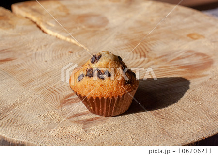 Muffin with raisins on a wooden stand in the sun. Homemade baking. Selective focus on the cupcake. Horizontal. Muffin with raisins on a wooden stand in the sun. Homemade baking. Selective focus on the cupcake. Horizontal. 106206211