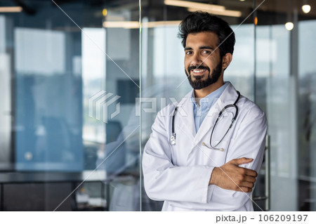 Portrait of a young Indian veterinarian doctor who stands smiling in the office, folded his arms and confidently looks at the camera. Portrait of a young Indian veterinarian doctor who stands smiling in the office, folded his arms and confidently looks at the camera. 106209197