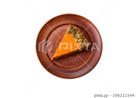 Beautiful tasty pumpkin pie with slices on a black ceramic plate 106211544