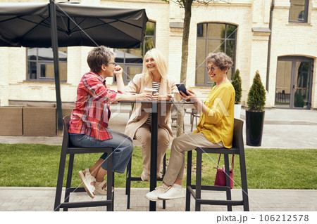 Mature female friends sitting in cafe, drinking coffee and laughing while enjoying a break time 106212578