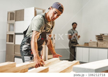 Young carpenter man looking and choosing wood plank at workshop in carpenter wood factory Young carpenter man looking and choosing wood plank at workshop in carpenter wood factory 106212718