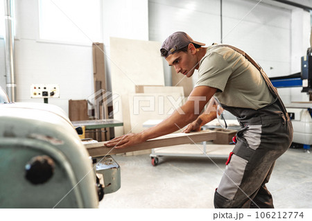 Male carpenter using some woodworking tools for his work in a factory 106212774