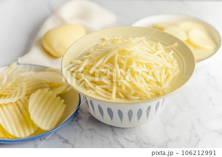 Potato, shredded potato, and potato chips placed on a marble slab. 106212991