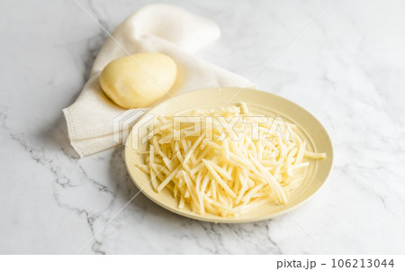 Potato and shredded potato placed on a marble slab. 106213044