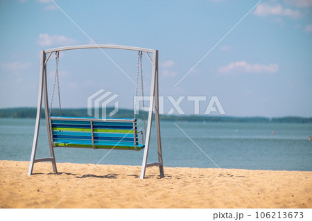 Empty metal swing on the sandy beach near the sea 106213673