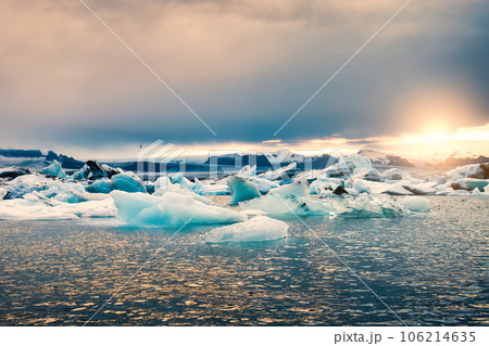 Sunset shining over Jokulsarlon glacier lagoon with blue iceberg at Iceland Sunset shining over Jokulsarlon glacier lagoon with blue iceberg at Iceland 106214635