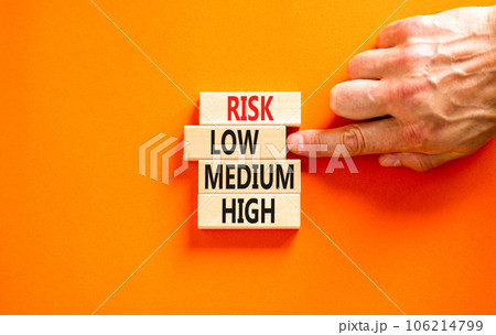 Time to low risk symbol. Concept word Risk low medium high on wooden block. Businessman hand. Beautiful orange table orange background. Business time to low risk concept. Copy space. Time to low risk symbol. Concept word Risk low medium high on wooden block. Businessman hand. Beautiful orange table orange background. Business time to low risk concept. Copy space. 106214799